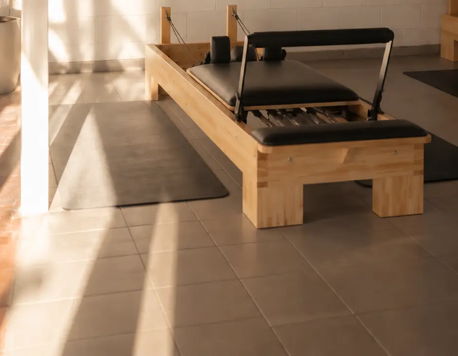 Reformer de madera y cuero negro bajo la luz del sol que entra al estudio